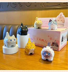 Detail of six wood-carved style resin cat figurines with faceted geometric surface