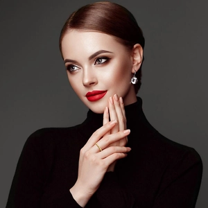 Close-up of elegant gold ring and silver gemstone earrings worn by a fashion model