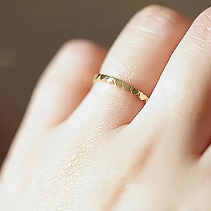 Minimalist gold ring with continuous heart patterns shown on a female finger