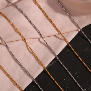 Detailed view of gold and silver box chains on silk and dark matte backgrounds