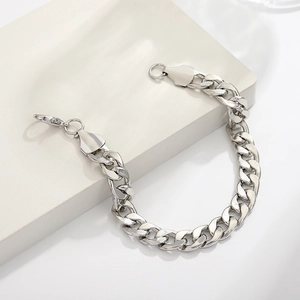 Sleek silver Cuban link bracelet with lobster clasp on minimalist geometric stand