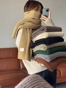 Detail showing ribbed knit scarves in camel, beige, and brown with a small logo label
