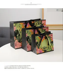Three-piece floral gift bag set with gold handles and black ribbon bow detail