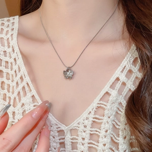 Close-up of a silver flower pendant necklace with pearl center worn on a model
