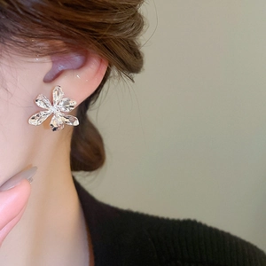 Detailed view of silver 3D flower stud earring with textured metal on ear model
