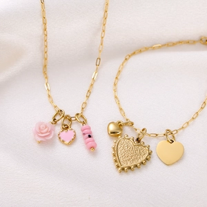 Detail of gold layered necklaces with pink heart and gold textured heart pendants