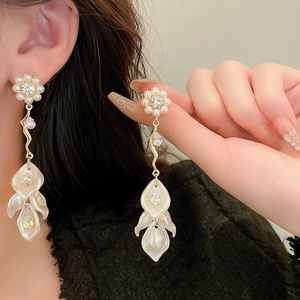 Detail of floral drop earrings with pearls and rhinestones on model and hand
