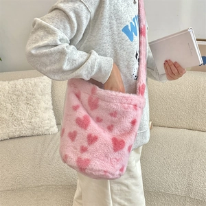 Detail of pink plush bucket bag with heart patterns worn as a crossbody by a model