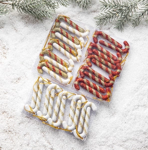 Glittered Christmas candy cane ornaments in red and gold on snowy background