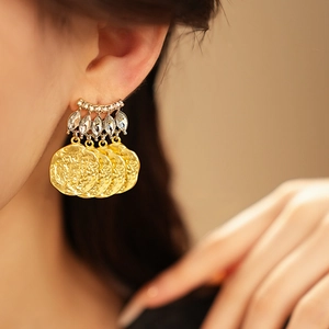Detail of vintage gold earrings with sparkling rhinestones and wavy round fringe pendants