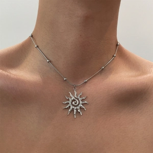 Silver hollow sun pendant necklace with snake bead chain on a female collarbone