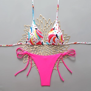 Detail of printed bikini top and bright pink tie-side bottoms on a grey surface