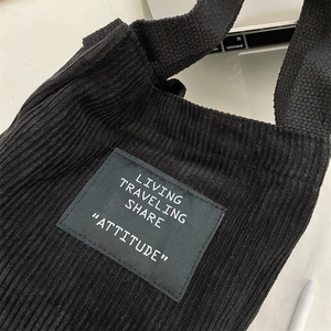 Gros plan détaillé sur la texture du velours côtelé noir et l'écusson du sac seau