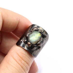 Macro shot of a vintage bohemian ring with a labradorite stone on a model's finger