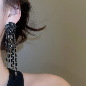 Détail de boucles d'oreilles noires à pompons longs avec oxydes de zirconium