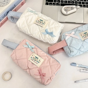 Quilted glossy nylon pouch with ribbon bow and soft macaron colors on a desk