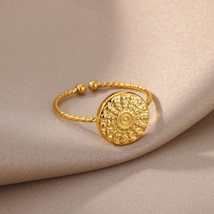 Detailed view of an 18k gold plated stainless steel spiral ring with a sunburst textured disc