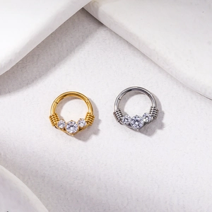 Detail of gold and silver G23 titanium nose rings with cubic zirconia inlay and wire wrap