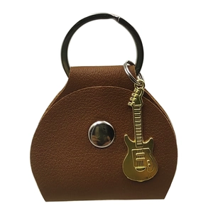 Macro shot of brown leather guitar pick holder with a golden guitar pendant and silver ring