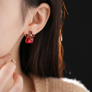 Close-up of vintage flower stud earring with red crystal on model's ear