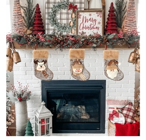 Three hanging linen Christmas stockings featuring 3D Santa, snowman, and reindeer on a fireplace
