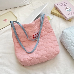 Vue macro du sac fourre-tout rose matelassé avec anses en denim bleu et étiquette