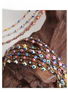 Macro shot of colorful evil eye enamel charms on a golden stainless steel chain