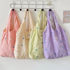 Detail of embroidered colorful bows on textured seersucker tote bags in pastel shades