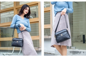 Detailed view of women's black floral embossed crossbody shoulder bag worn by model outdoors.