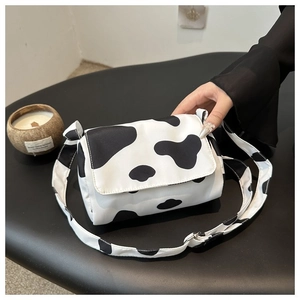 Detail of trendy small square crossbody bag featuring a classic black and white cow pattern