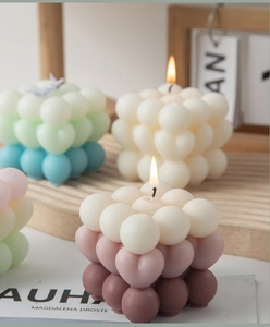 Close-up of cube bubble candles in blue, beige and pink gradients on a wooden tray