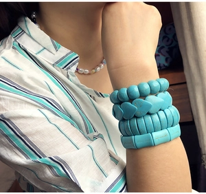 Close-up of stacked turquoise bead bracelets featuring round and heart shapes on wrist