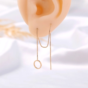 Macro shot of gold box chain earrings with circular pendants on a silicone ear model