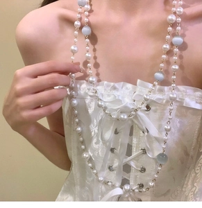 Detailed view of baroque pearls and blue cat eye beads on a layered gold necklace