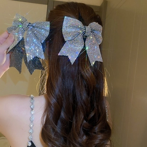Detailed view of a sparkling bow hair clip with silver rhinestones on a female model