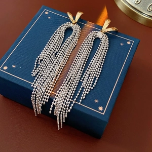 Close-up of 18k gold-plated rabbit ear studs with silver beaded tassel fringe detail