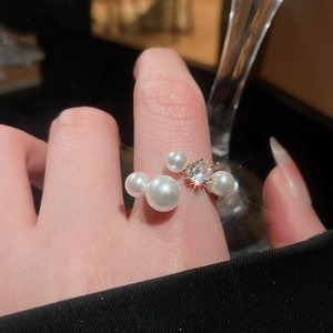 Macro shot of an open gold ring featuring multiple pearls and a sparkling zircon stone
