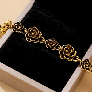 Macro shot of vintage gold rose bracelet detailing hollow metal flowers on black velvet