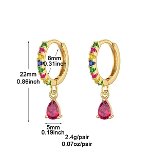 Détail de créoles dorées avec pierres arc-en-ciel et pendentif rouge en forme de poire