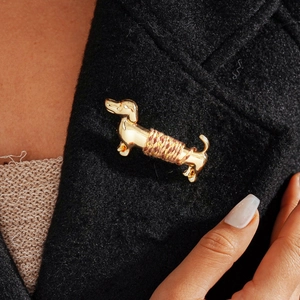 Detail shot of golden dachshund brooch with brown thread wrap on black blazer lapel