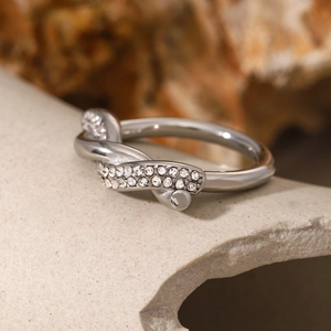 Detailed view of silver twist ring featuring pave-set zircons on textured stone background