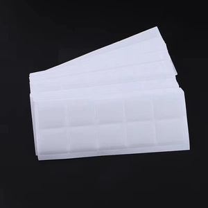 Macro shot of grid-arranged double-sided adhesive nail glue tabs on black background