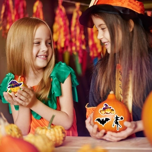 Kids in costumes decorating pumpkins with festive Halloween stickers and holiday decals