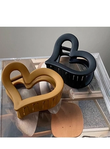 Detail of matte heart-shaped hair claw clips in black and mustard yellow finishes
