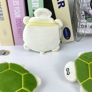 Detail view of plush turtle coin purse showing soft green shell and yellow zipper closure