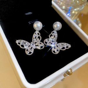 Macro detail of silver butterfly earrings with sparkling cubic zirconia and pearl accents