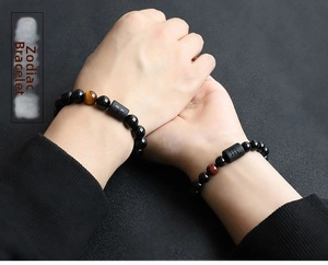 Detail of couple bracelets with 8mm black beads, tiger eye stones and zodiac carvings