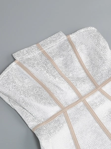 Détail macro du tissu jacquard scintillant argenté sur une robe bandage blanche chic