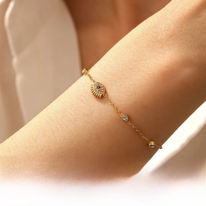 Close-up of a gold-plated evil eye bracelet with diamonds on a model's wrist