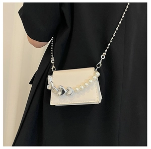 Detail of a mini cream PU crossbody bag with silver heart and pearl chain strap